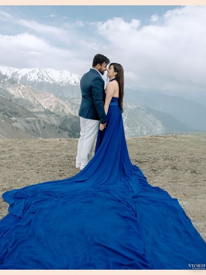 A full-length shot of the couple, the bride's long blue train spread out on the snow, with the Himalayas in the background.