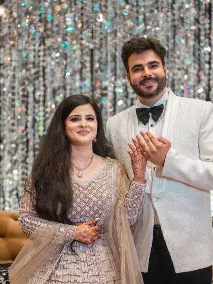 A beautiful portrait of the newly engaged couple, holding hands and smiling, with a glittering crystal backdrop.