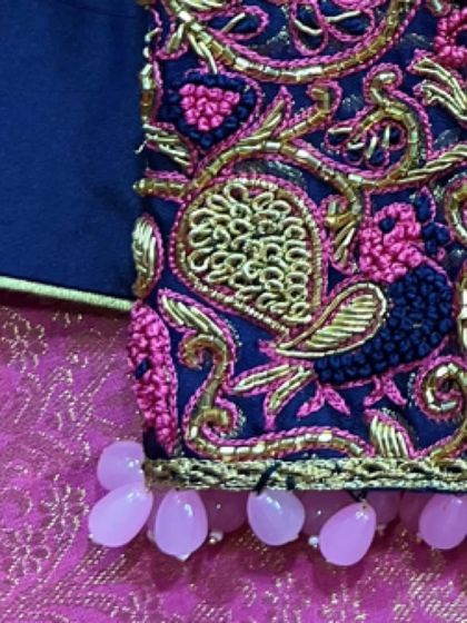 The finishing touch of pearl drop tassels on the sleeve of this navy blue blouse adds a touch of elegance and movement.