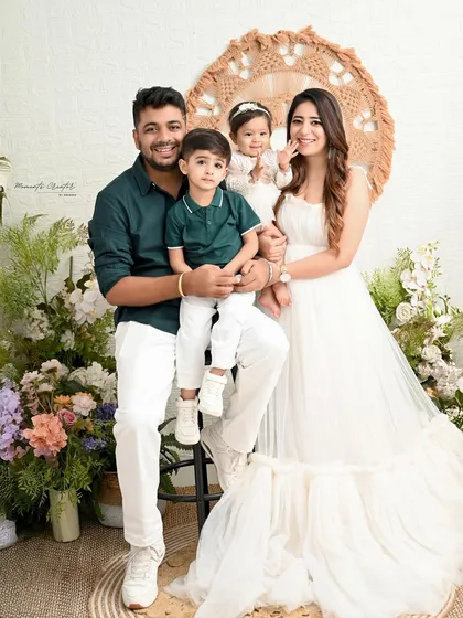 A bright and happy family photo. Their smiles are infectious in this beautifully lit studio portrait with a clean, white and floral background.