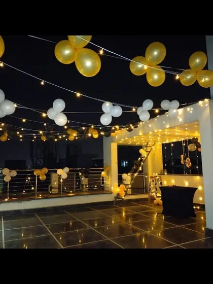 A simple yet elegant terrace decoration using strings of white and yellow balloons and fairy lights to create a beautiful open-air party space.