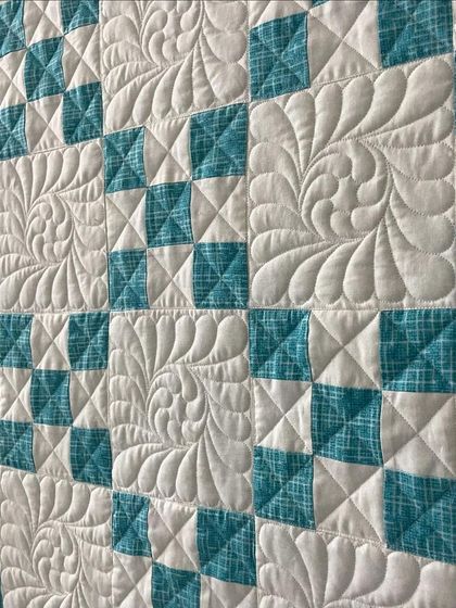 A close-up of the 9-patch quilt, where we've used a combination of feather and crosshatch quilting.