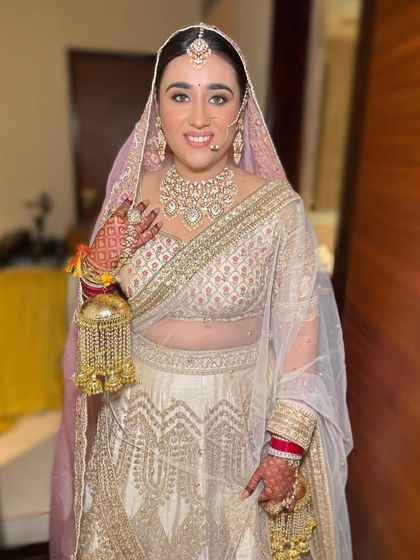 A real bride looking stunning in her white and gold wedding lehenga, complete with traditional kaleeras.