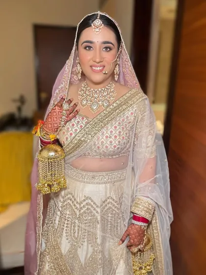 This bride looks absolutely regal in her white and gold lehenga. The polki necklace, maang tikka, and traditional kalire come together to create a stunning and complete bridal look.