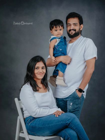 A classic family portrait with a casual, modern feel. The simple white shirts and jeans create a cohesive look that keeps the focus on their happy faces.