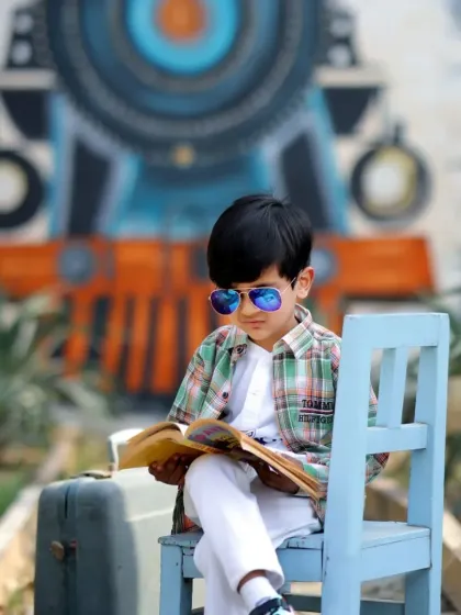 A focused young boy reading a book while waiting for his train in our creative, railroad-themed outdoor setup.