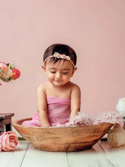 A shy, sweet smile in a bowl of flowers. I use props like this wooden bowl to create cozy and adorable poses for sitter-age babies.