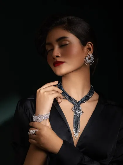 A soft, elegant pose highlighting the diamond bracelet and the unique design of the necklace.
