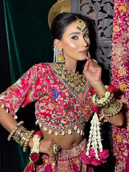 This image highlights the intricate details of the blouse and the beautiful floral hand jewelry, paired with a sharp, defined makeup look.