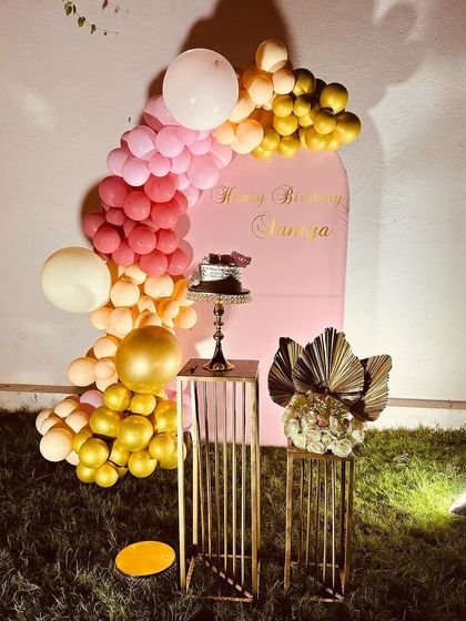 A simple arched backdrop with a colorful balloon garland. This setup is perfect for outdoor parties or as a cake-cutting backdrop.