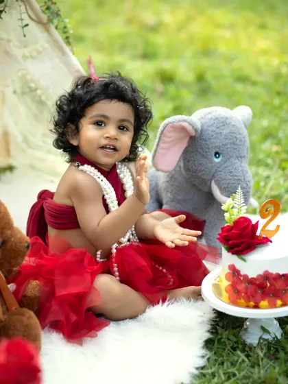 A sweet and happy portrait of the birthday girl. Her curly hair and bright smile are the centerpiece of this fun-filled second birthday cakesmash.