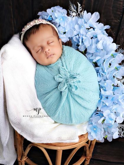 A wider shot showing the baby posed on a rattan stool, creating a beautiful, elevated portrait.