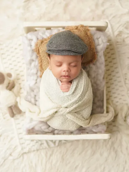The little gentleman is swaddled and sleeping in a tiny bed. This shows how a simple prop like a hat can define a whole theme.