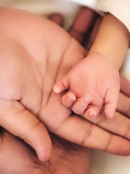A close-up of a newborn's tiny hand nestled in their parent's palm. These detail shots are a beautiful way to remember how small they were.