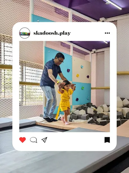 Guided by love, safeguarded with joy. A parent helps their little one take their first tentative steps on the trampoline, a beautiful moment of bonding and trust.