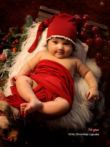 "I'm your little Christmas cupcake." This baby is all smiles while lying in a bed of soft fur and festive red decorations.