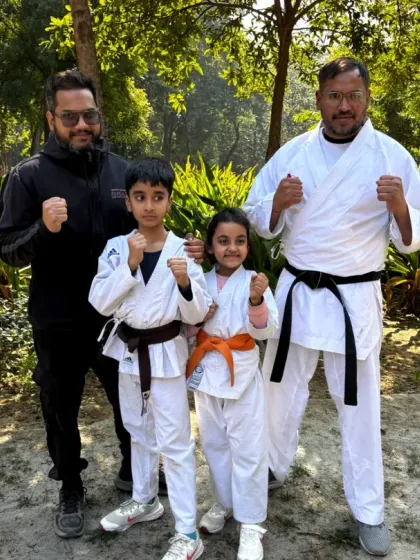 Our coaches with two young karate students, one a brown belt and the other an orange belt. We are proud to guide the next generation of martial artists.