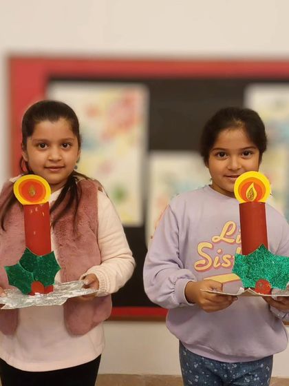 More happy students with their Christmas candle crafts. Each one is unique, decorated with glittery holly leaves and a bright paper flame.