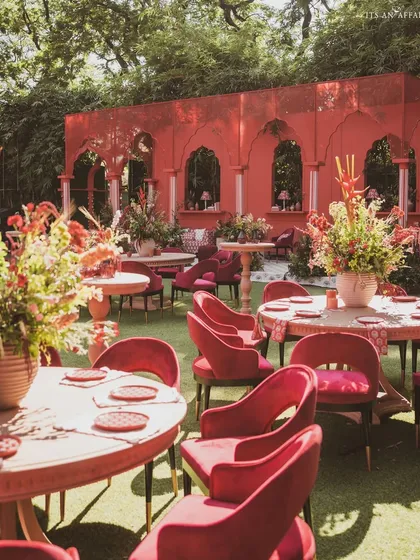 The dining area for the 'Gulal Bagh' wedding, where tables are set with plush red velvet chairs, creating a rich, monochromatic look.