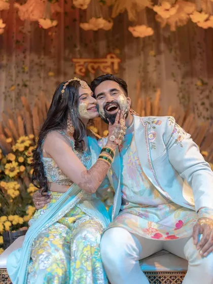 A playful and happy couple at their Haldi, with the bride's floral shela adding a touch of elegance.