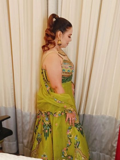 A side view of the client's high ponytail, showing the volume and texture of the curls. This is a glamorous and comfortable style for any festive occasion.