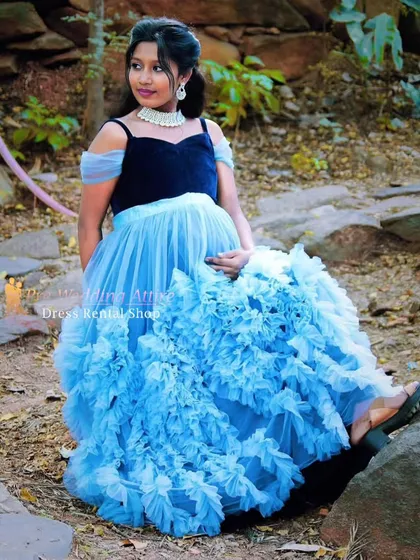 A seated portrait in our blue ruffled gown, showcasing the off-the-shoulder velvet bodice and the voluminous tulle skirt. It's a comfortable yet glamorous option for your maternity photoshoot.