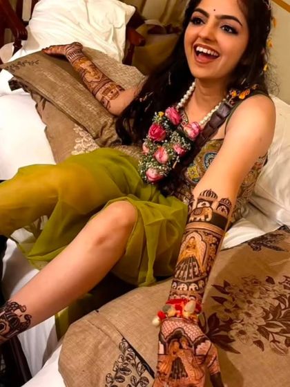 A relaxed and happy bride, her full bridal mehndi on display. The design covers both her arms and legs.
