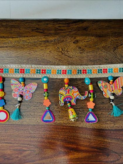 The 'Bageecha Toran' laid out on a wooden table, giving a clear view of its intricate details and craftsmanship.