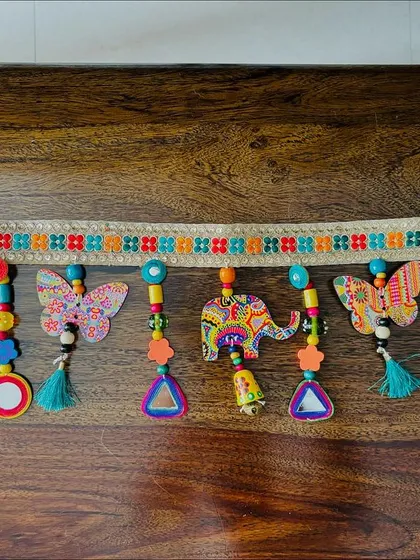 The 'Bageecha Toran' laid out on a wooden table, giving a clear view of its intricate details and craftsmanship.