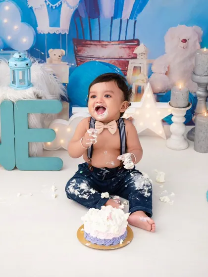 A messy and happy cake smash. The bow tie and suspenders add a touch of dapper charm to this fun-filled first birthday moment.