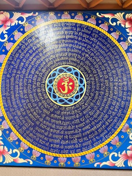 A full view of the 'Om' and Navkar Mantra painting installed in the client's office. The vibrant blue and intricate gold lettering create a focal point that is both beautiful and spiritually uplifting.