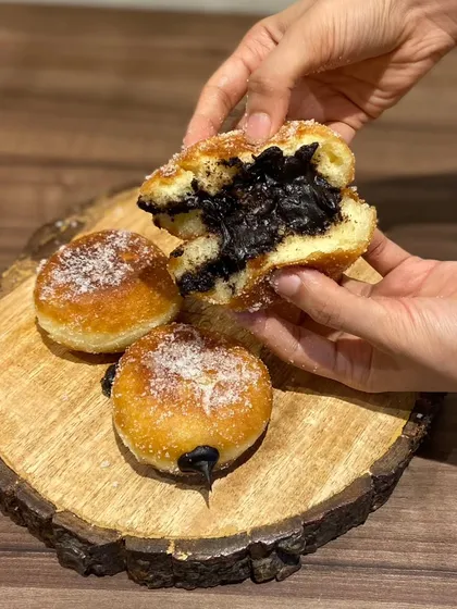 Our heavenly chocolate-filled donuts, also known as bomboloni. These soft, sugar-dusted donuts are generously filled with a rich, dark chocolate cream.