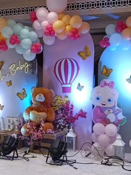 A pastel-themed baby shower with a hot air balloon motif, teddy bears, and butterfly accents against a purple backdrop.
