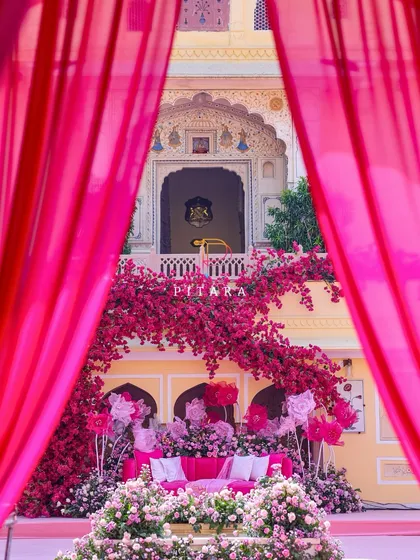 A peek through the curtains reveals the stunning floral stage, perfectly framed by the palace architecture. This shot captures the layers of our design, from the grand entrance to the intimate seating area.