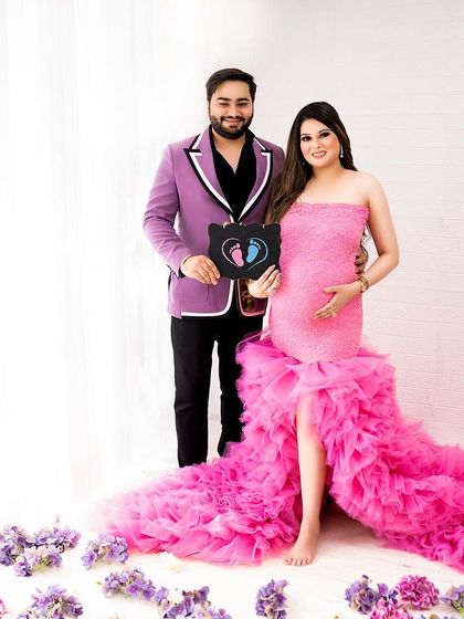 A fun and celebratory shot announcing the baby's gender with a cute sign. The full length of the incredible pink ruffled gown is on display here.