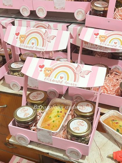 A closer look at the "O-N-E-derful" first birthday hampers, showing the fruit dry cake and jars of treats inside the pink cart.