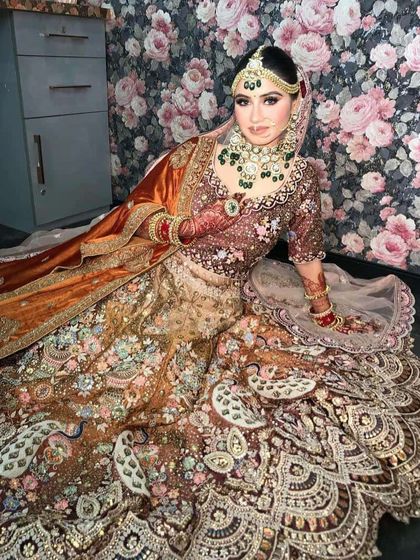 A seated pose showing the full spread of the peacock lehenga's skirt.