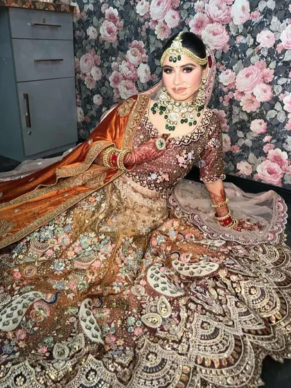A seated pose showing the full spread of the peacock lehenga's skirt.
