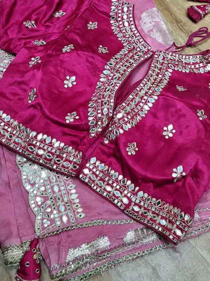 A close-up of a stunning pink blouse with heavy mirror work, designed to complement our festive sarees. The craftsmanship on the neckline and sleeves is simply exquisite.