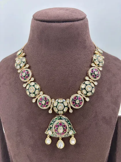 A beautiful meenakari necklace with a large pendant, featuring green and red enamel work.