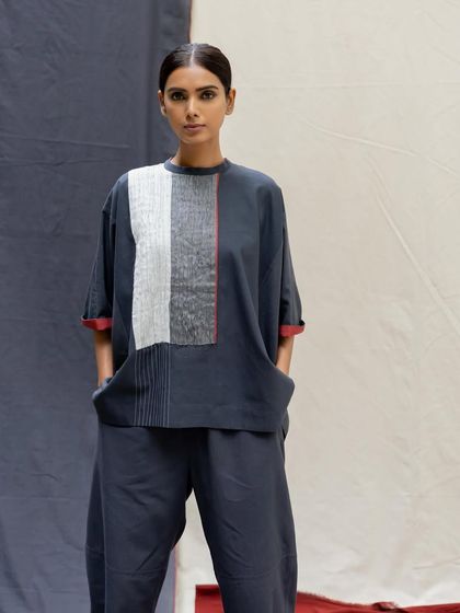 A model in a relaxed-fit co-ord set in charcoal grey, featuring a top with a textured, color-blocked panel.