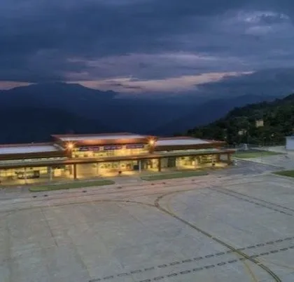 The Pakyong Airport terminal at dusk. The design is simple and functional, built to withstand the region's weather while providing a clear, welcoming space for travelers. The lighting is designed to be efficient and non-intrusive to the surrounding environment.