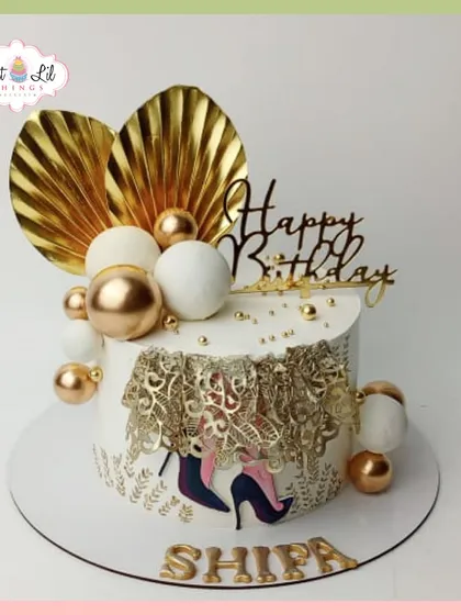 A glamorous birthday cake for Shilpa, featuring a gold lace design, high heels, and a cascade of gold and white spheres.