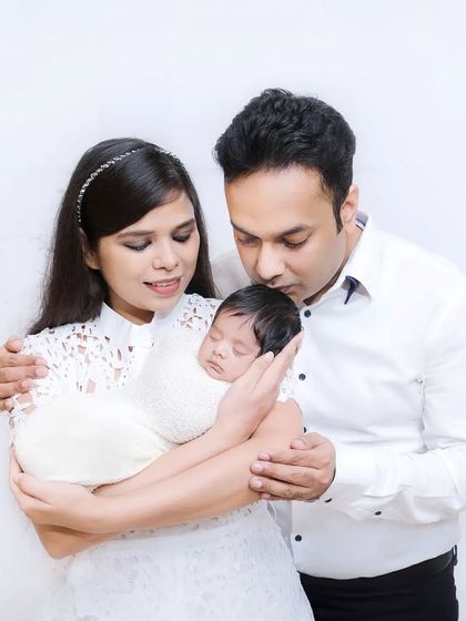 A tender moment with new parents cradling their sleeping newborn. The all-white theme gives this first family portrait a pure and serene quality.