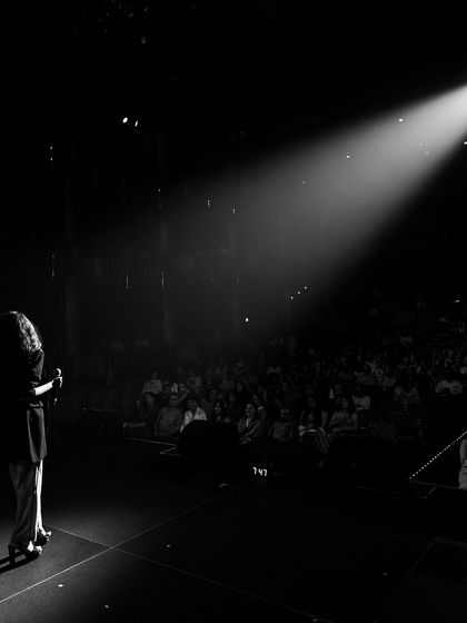 Alone on the stage, addressing a full house. A powerful moment that captures the connection between a performer and the audience.
