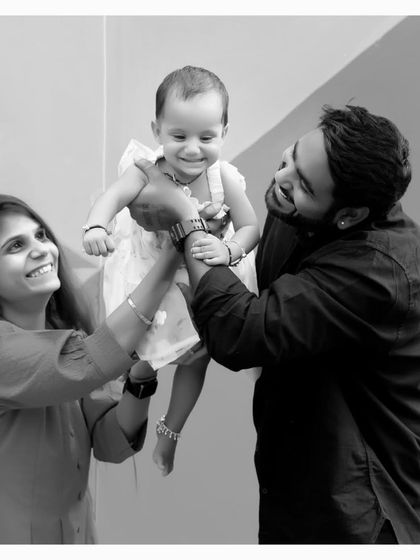 A beautiful black and white photo of parents lifting their smiling baby. This classic family portrait captures a moment of pure joy and connection.