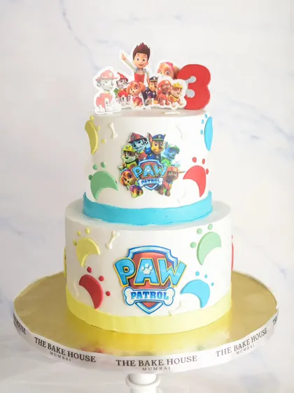 A fun two-tiered Paw Patrol cake for a third birthday. This cake uses edible prints of the characters and colorful paw prints to bring the theme to life with minimal fondant.