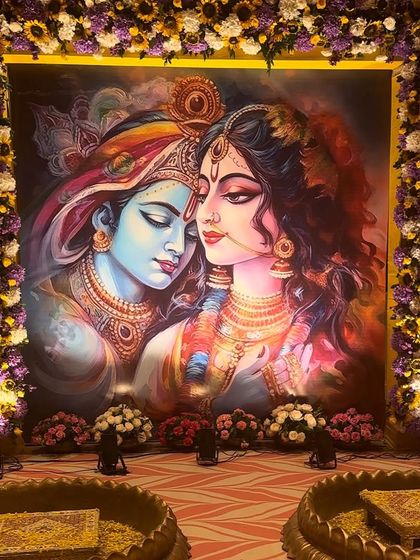 A closer view of the divine Radha Krishna backdrop. The rich colors of the painting are complemented by the vibrant floral frame, creating a perfect setting for a sacred Haldi function.