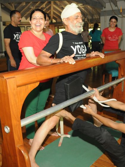 This gentleman is using a specialized wooden prop, the 'horse', to work on his leg and hip alignment. Such props, invented by Guruji, allow us to isolate and correct specific misalignments that are the root cause of pain.