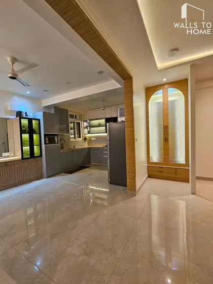 An open-plan living and kitchen area with a minimalist aesthetic. The grey kitchen cabinets and integrated bar unit create a cohesive and modern living space.